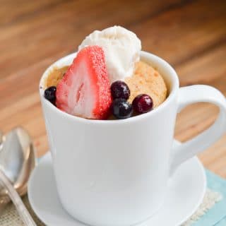 Paleo mug cake with berries and ice cream in mug.