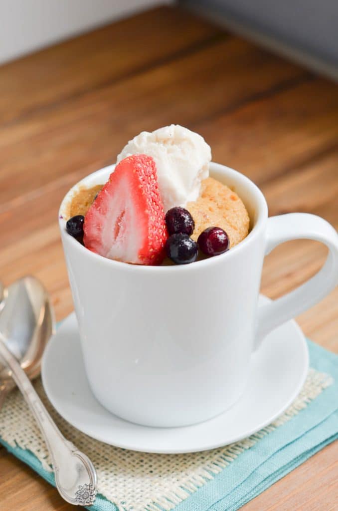 Paleo mug cake with berries and ice cream in mug.