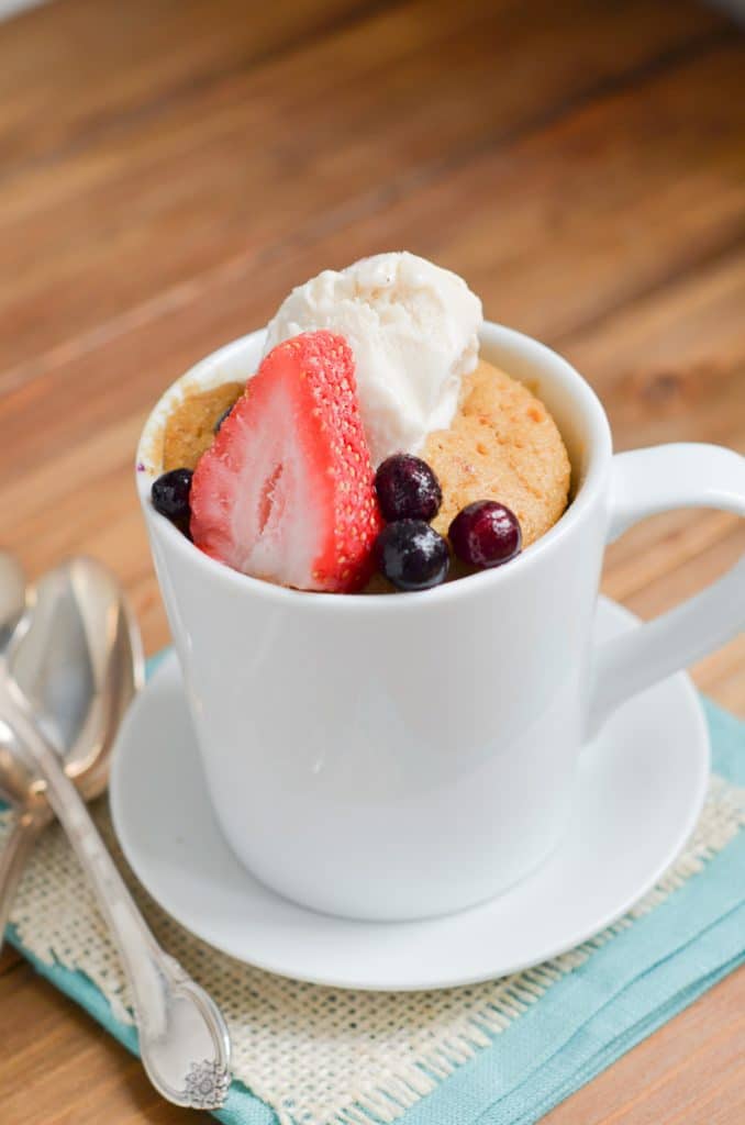 Paleo mug cake with berries and ice cream in mug.