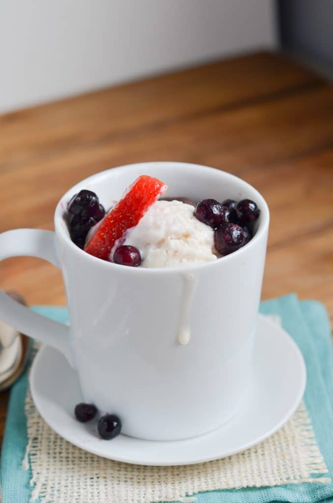 Paleo chocolate mug cake with berries and ice cream in mug.