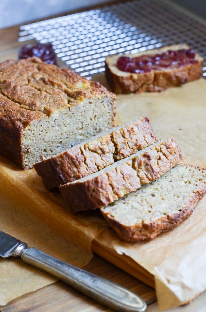 Banana bread with slices on chopping block.