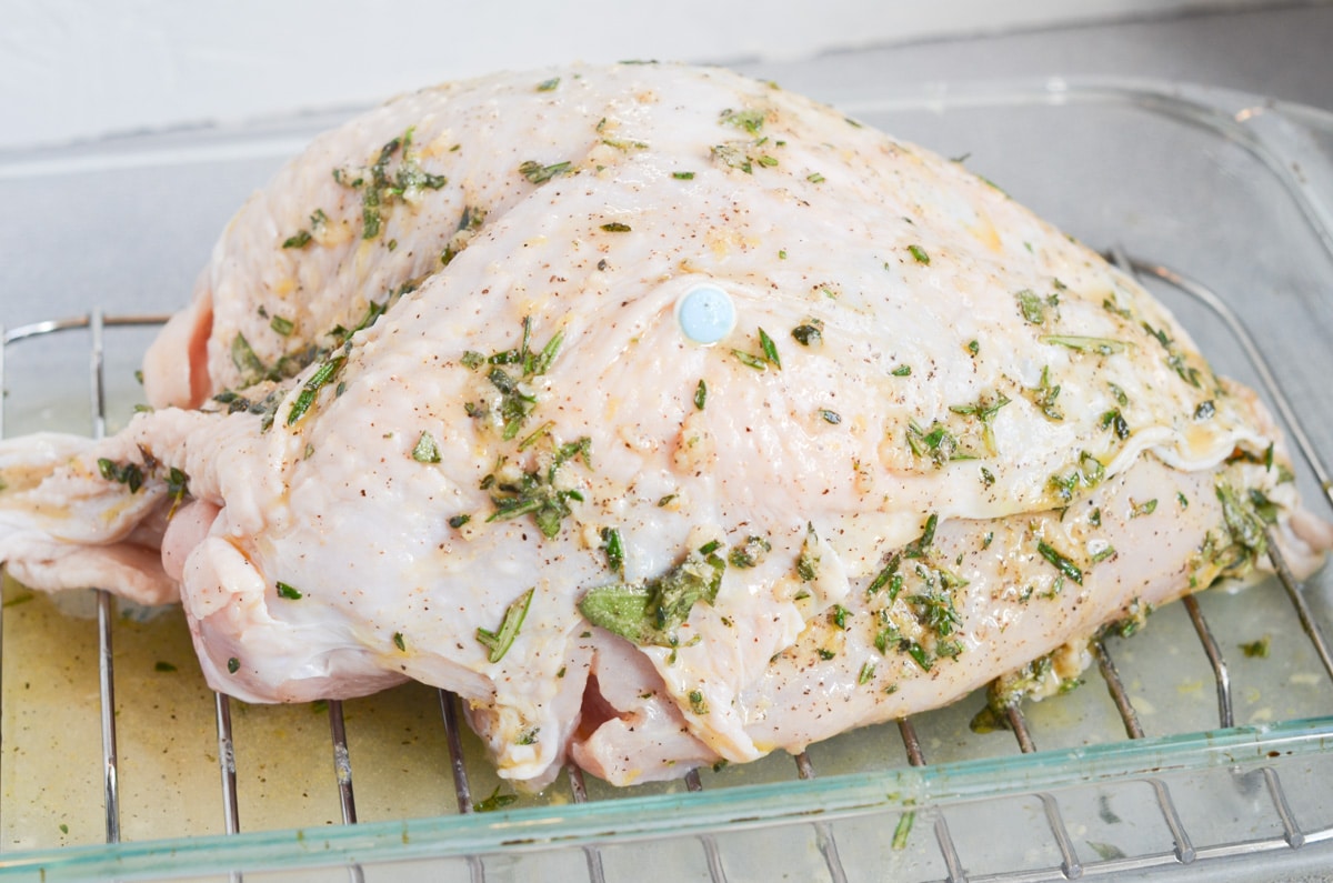 herb mixture all over uncooked turkey breast in roasting pan.