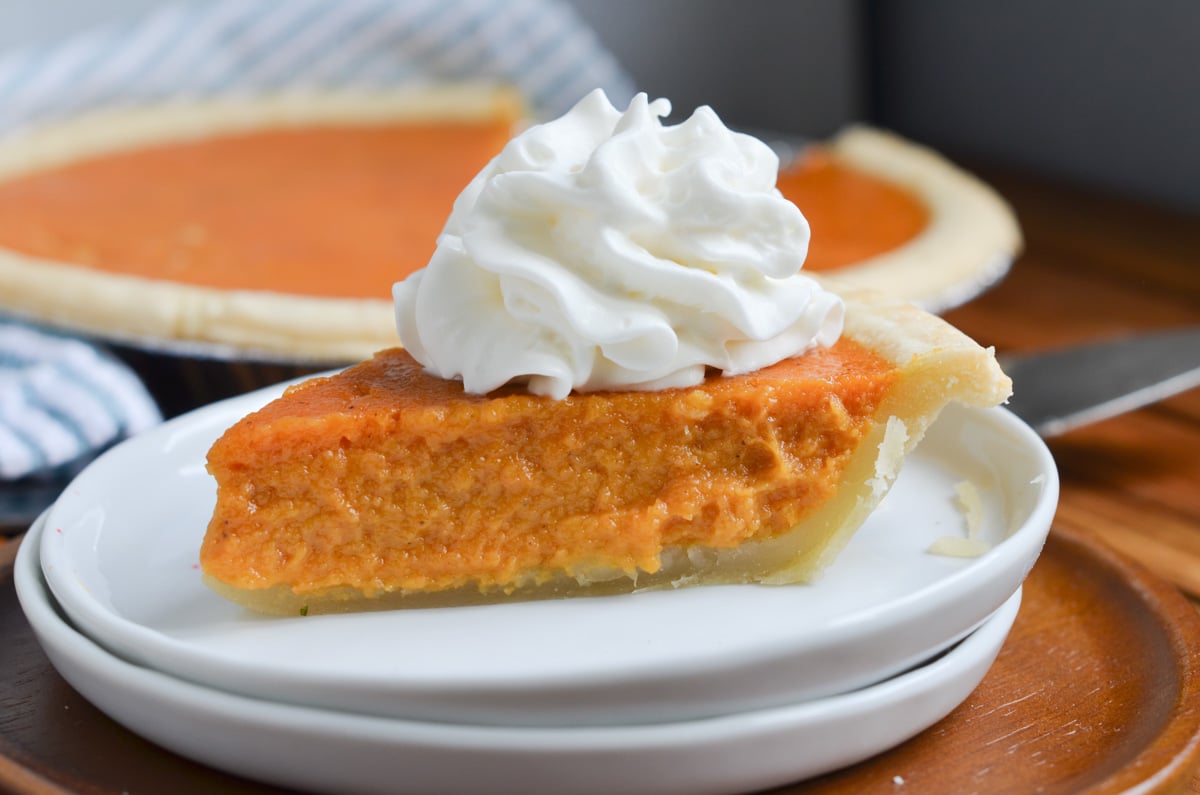 Sweet Potato pie slice on a plate with whipped cream.