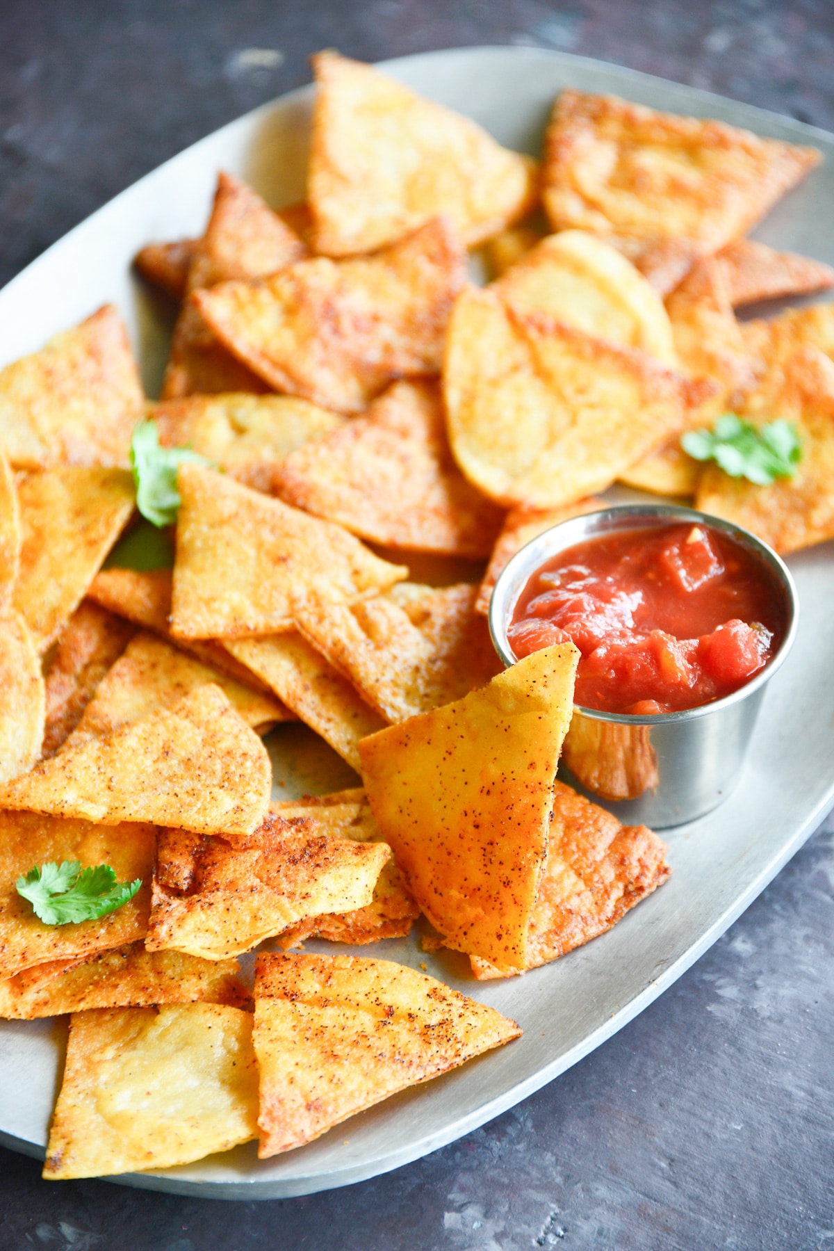 baked tortilla chips on a platter with salsa.