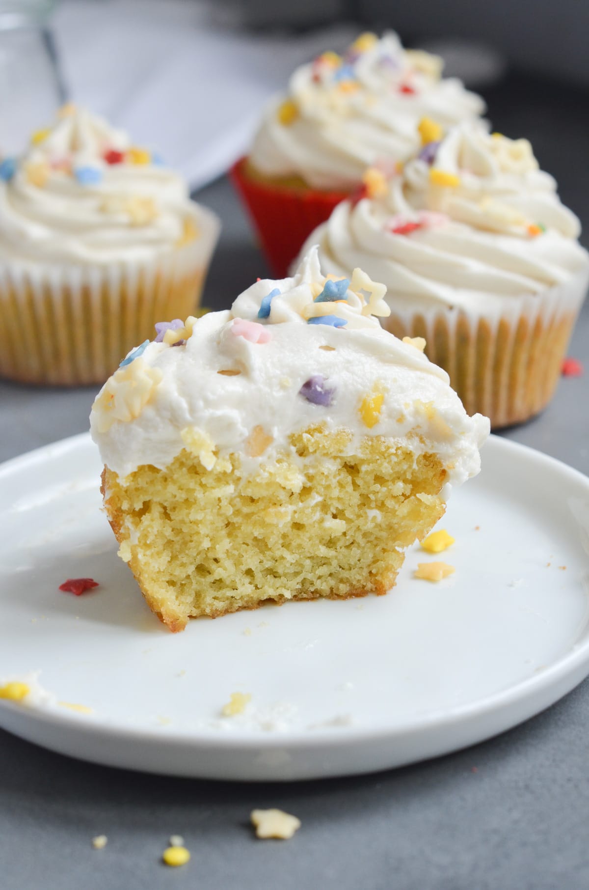 half a coconut flour cupcake with frosting on a plate.