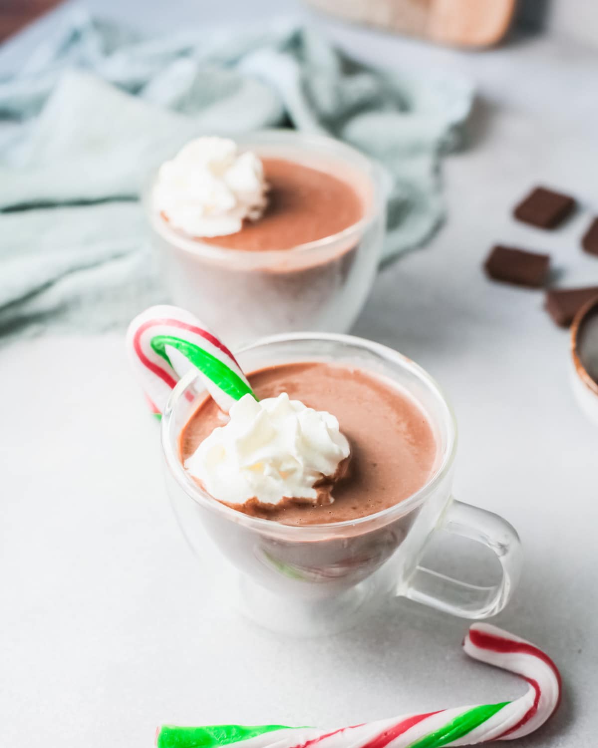 hot chocolate in a mug with whipped cream and candy cane.