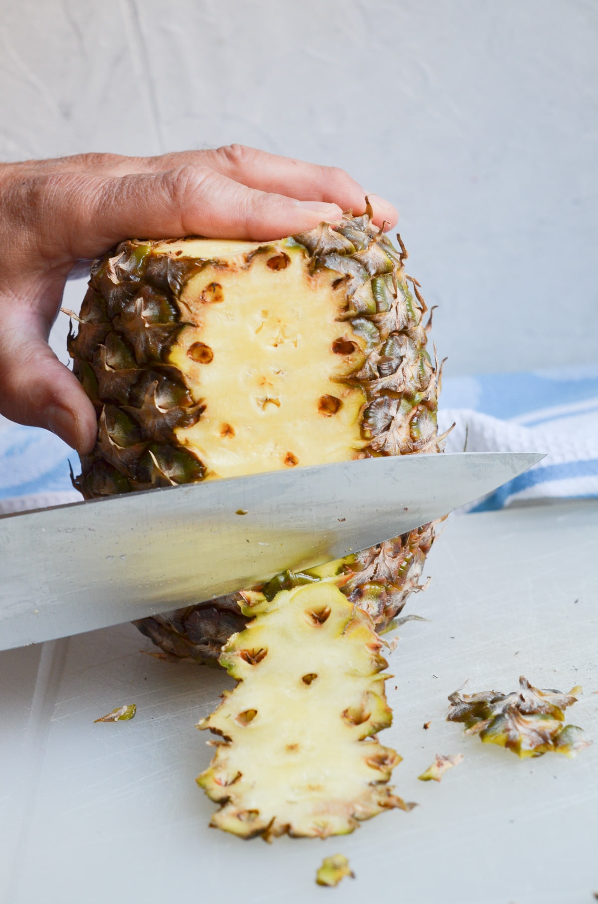 slicing side skin off the pineapple.