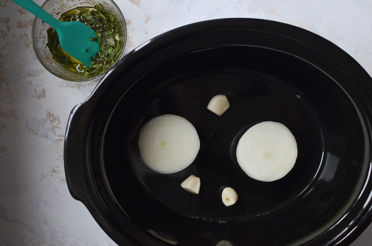 onion and garlic in bottom of slow cooker.